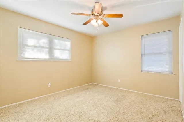 an empty room with windows and chandelier fan