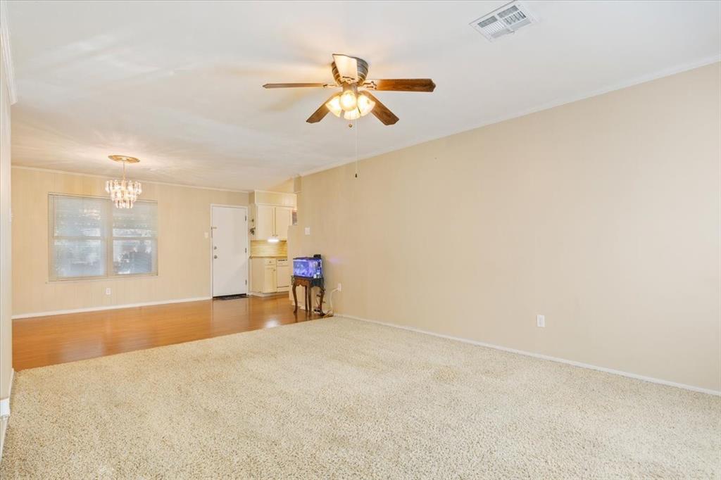6209 May Drive Waco, TX 76710 - Photo 8 of 30 Unfurnished living room featuring ceiling fan, carpet flooring, wood finished floors, ornamental molding, and a chandelier