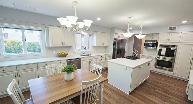 a kitchen with a white center island a stove a refrigerator cabinets and wooden floor