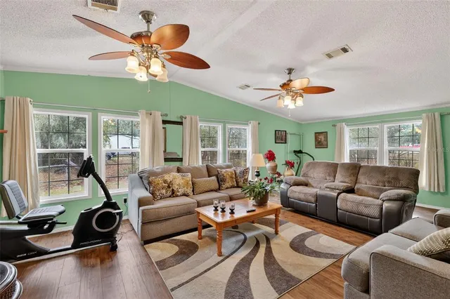 a living room with furniture ceiling fan and a large window