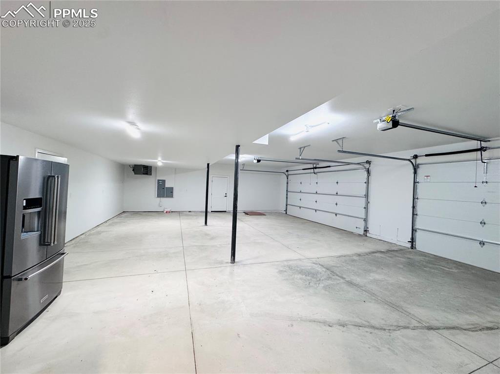 1282 South Crystal Road Lake George, CO 80827 - Photo 5 of 26 Garage with stainless steel refrigerator with ice dispenser, a garage door opener, and electric panel