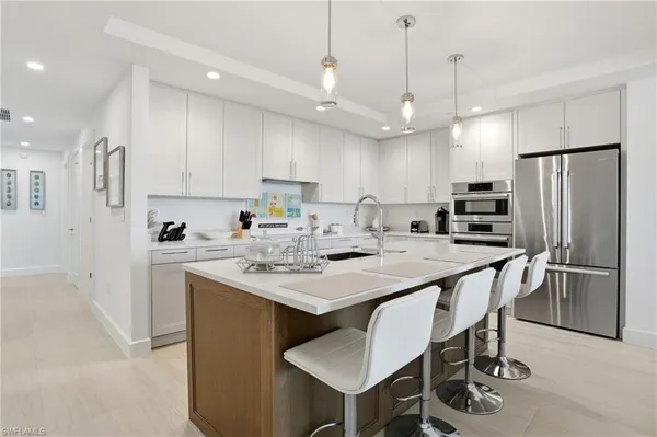 a kitchen with kitchen island a dining table chairs sink and cabinets