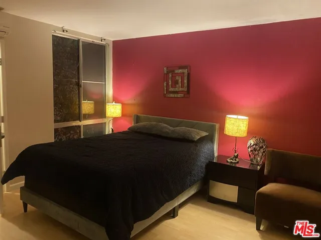 a bedroom with a bed and a lamp on dresser
