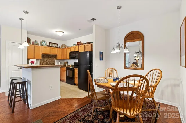 a kitchen with stainless steel appliances granite countertop a dining table chairs refrigerator and sink