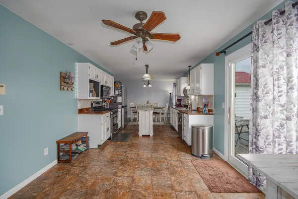 a view of a hallway with a livingroom with furniture and a ceiling fan