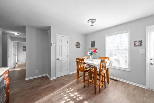a dining room with wooden floor a chandelier a wooden table and chairs