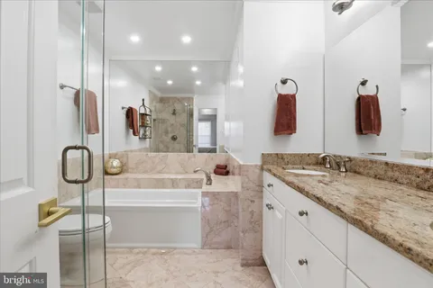 a bathroom with a granite countertop sink a toilet and shower