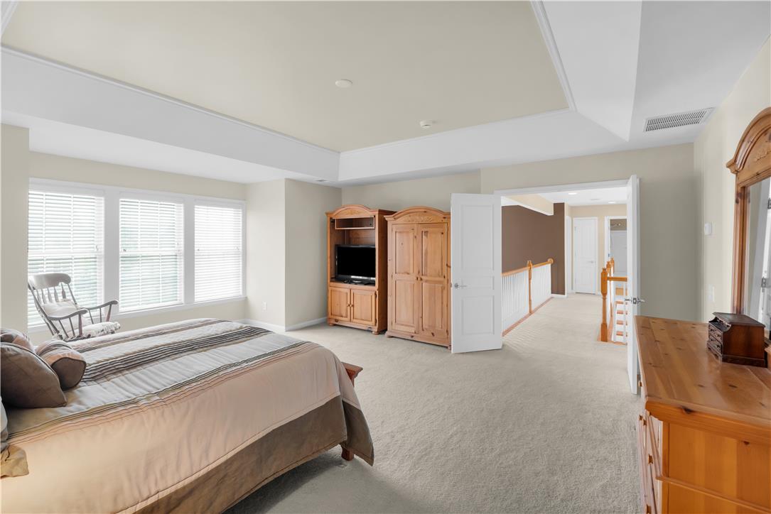 1709 Travers Road Breinigsville, PA 18031 - Photo 29 of 55 A tray ceiling elevates this naturally illuminated primary bedroom, offering a serene retreat with soft carpeting.