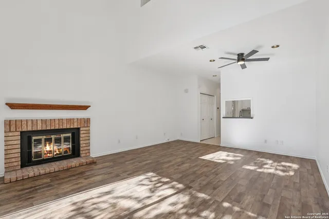 a view of an empty room with wooden floor fireplace and a window