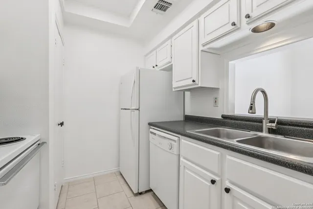 a kitchen with white cabinets and white appliances