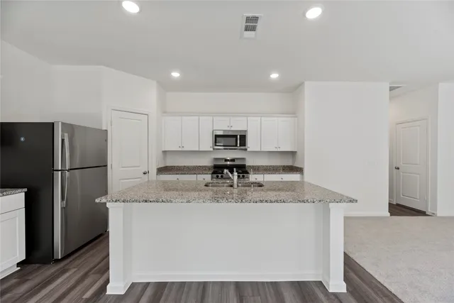 a kitchen with stainless steel appliances granite countertop a refrigerator a sink a stove a microwave and island