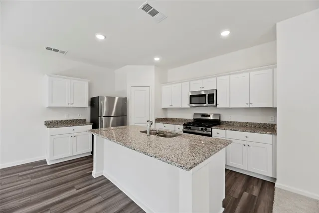 a kitchen with stainless steel appliances granite countertop a sink stove and refrigerator