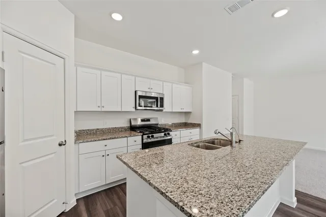 a kitchen with stainless steel appliances granite countertop a sink stove and cabinets