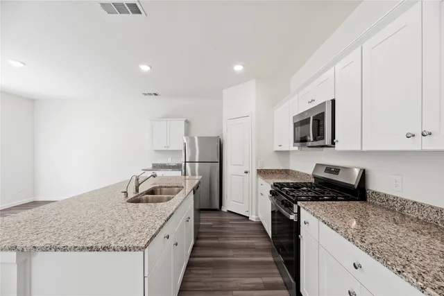 a kitchen with granite countertop sink stainless steel appliances and white cabinets