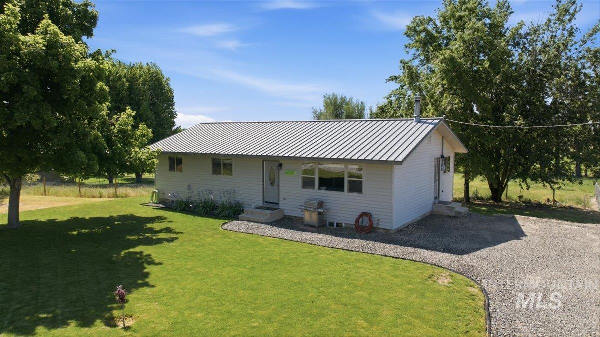 6323 Foothill Road Star, ID 83669 - Photo 48 of 50 White siding residence featuring a gray metal roof, gravel driveway, and a front lawn