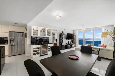 a living room with furniture a flat screen tv and a refrigerator