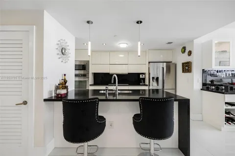 a kitchen with stainless steel appliances kitchen island granite countertop a refrigerator and a sink