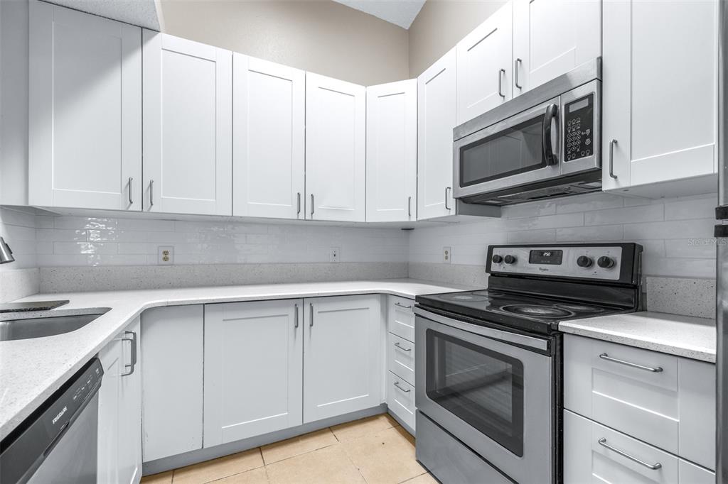 5100 Burchette Road, Unit 2505 Tampa, FL 33647 - Photo 13 of 47 a kitchen with white cabinets stainless steel appliances and sink