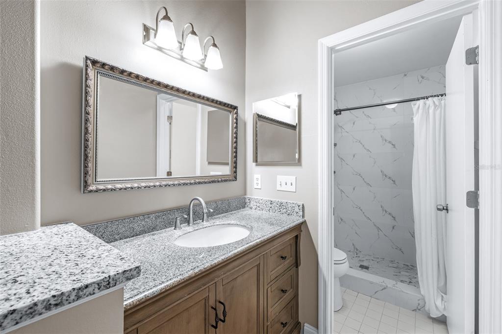 5100 Burchette Road, Unit 2505 Tampa, FL 33647 - Photo 22 of 47 a bathroom with a granite countertop sink a mirror a shower and a bathtub