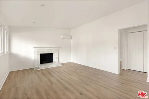 a view of an empty room with wooden floor and a fireplace