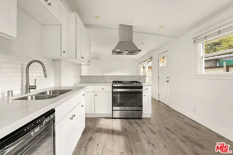 a kitchen with granite countertop a sink cabinets stainless steel appliances and a window