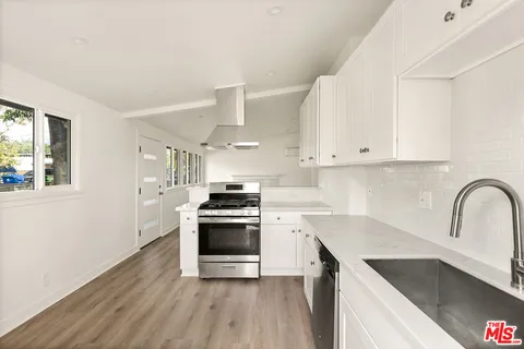 a kitchen with granite countertop a stove a sink and a refrigerator