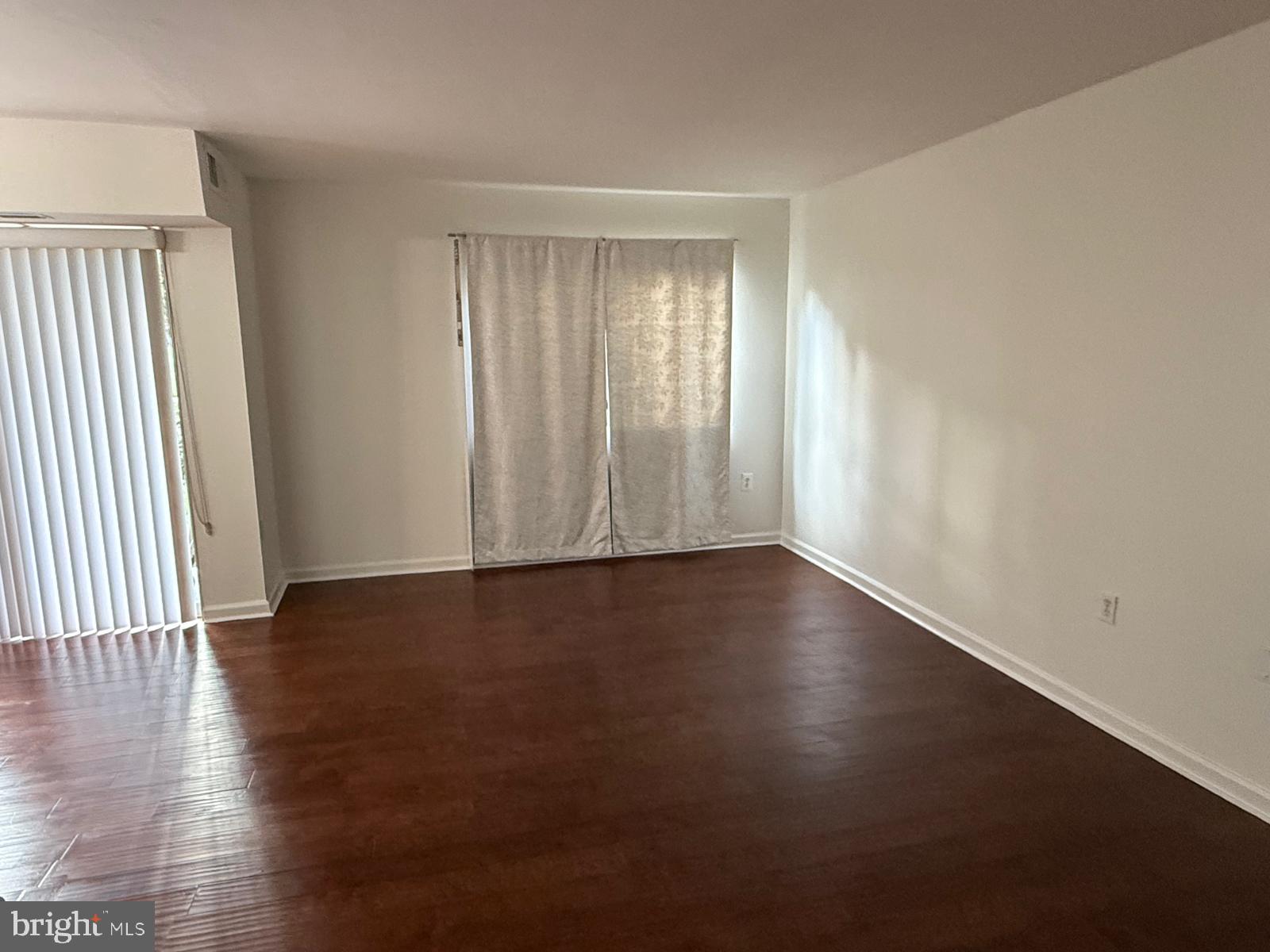 1604 Renate Drive, Unit 104 Woodbridge, VA 22192 - Photo 16 of 29 an empty room with wooden floor and windows with curtains