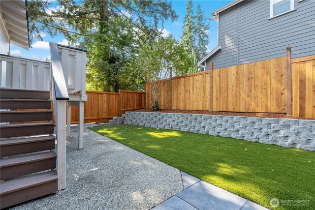 a view of a backyard with wooden fence and a large tree