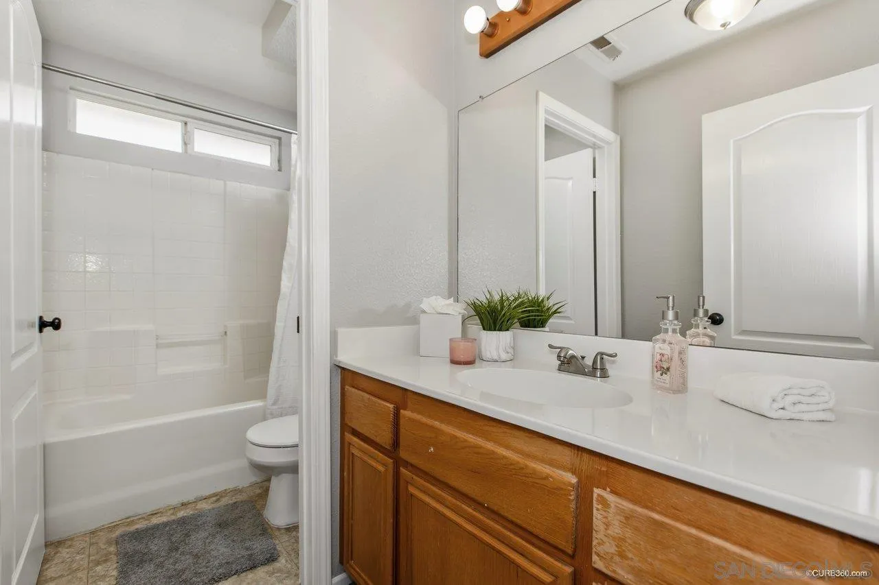 1867 McDougal Terrace El Cajon, CA 92021 - Photo 16 of 28 a bathroom with a granite countertop sink a toilet a mirror and shower