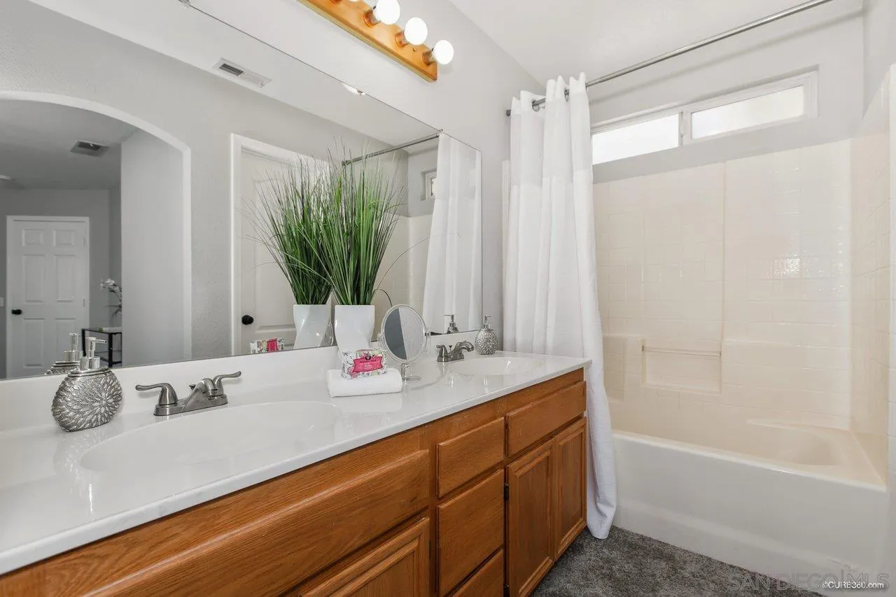 1867 McDougal Terrace El Cajon, CA 92021 - Photo 21 of 28 a bathroom with a double vanity sink a mirror and a bathtub