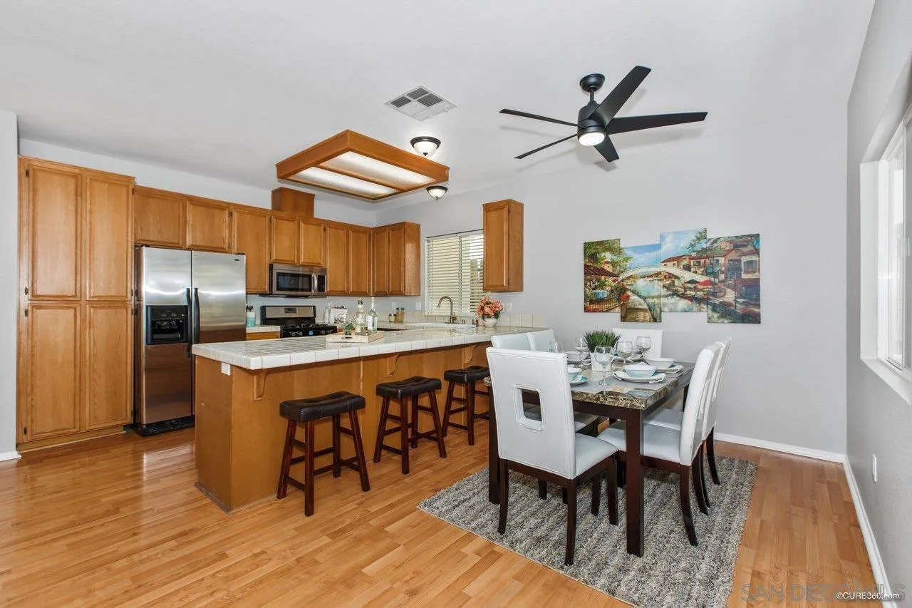 1867 McDougal Terrace El Cajon, CA 92021 - Photo 7 of 28 a kitchen with stainless steel appliances granite countertop a dining table chairs refrigerator and sink