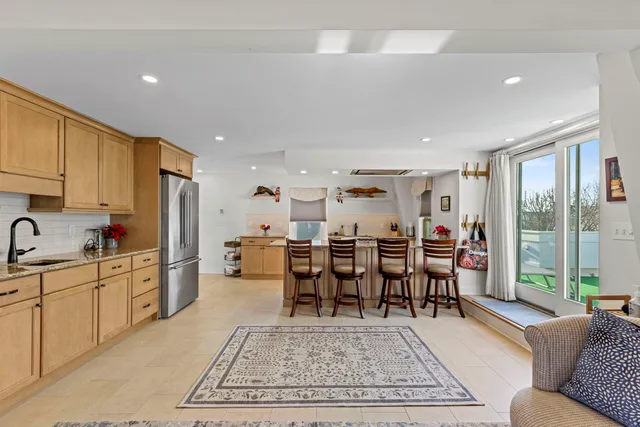 a living room with furniture a rug kitchen view and a large window