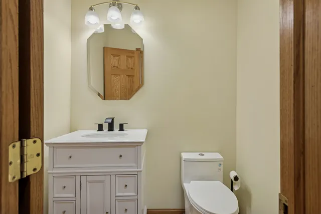 a bathroom with a toilet sink vanity and mirror