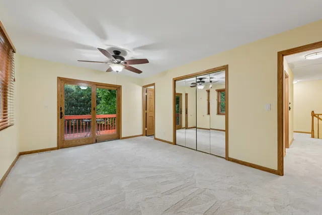 an empty room with chandelier fan and windows