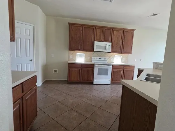 a kitchen with granite countertop a stove top oven microwave and cabinets