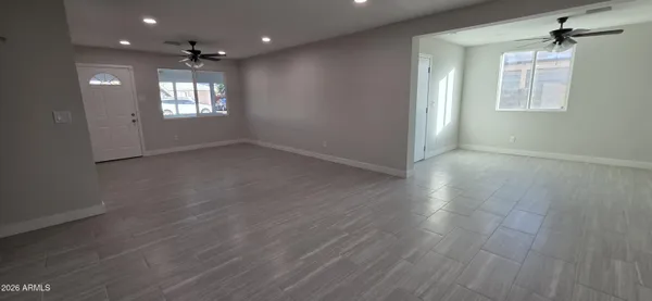 a view of an empty room with a window and wooden floor