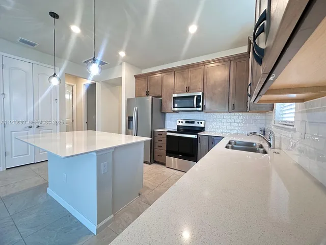 a large kitchen with kitchen island a sink stainless steel appliances and cabinets