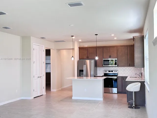 a kitchen with stainless steel appliances kitchen island granite countertop a refrigerator oven a sink a stove and white cabinets