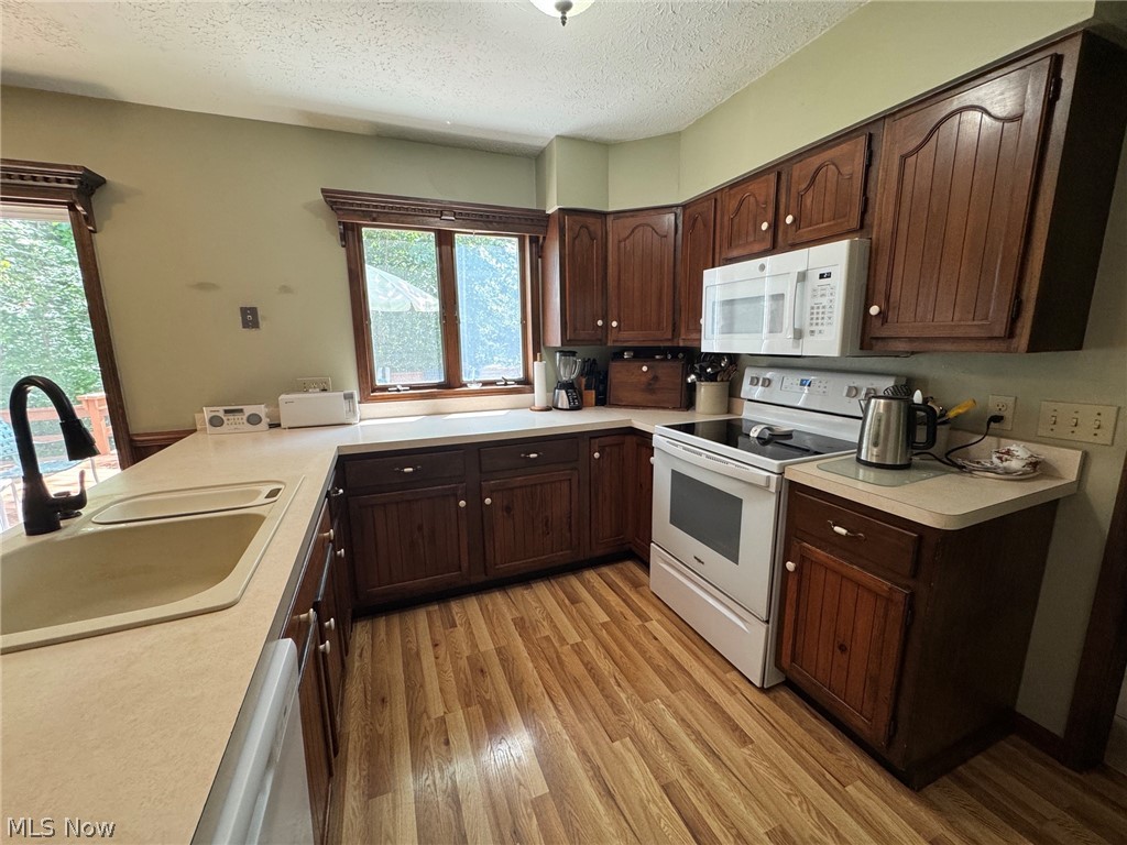 8201 Orchard Road Painesville, OH 44077 - Photo 9 of 45 Kitchen featuring wood-finish flooring, wood cabinetry with panel details, plenty of countertop space , and a window overlooking back yard