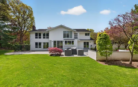 a front view of a house with a garden and trees