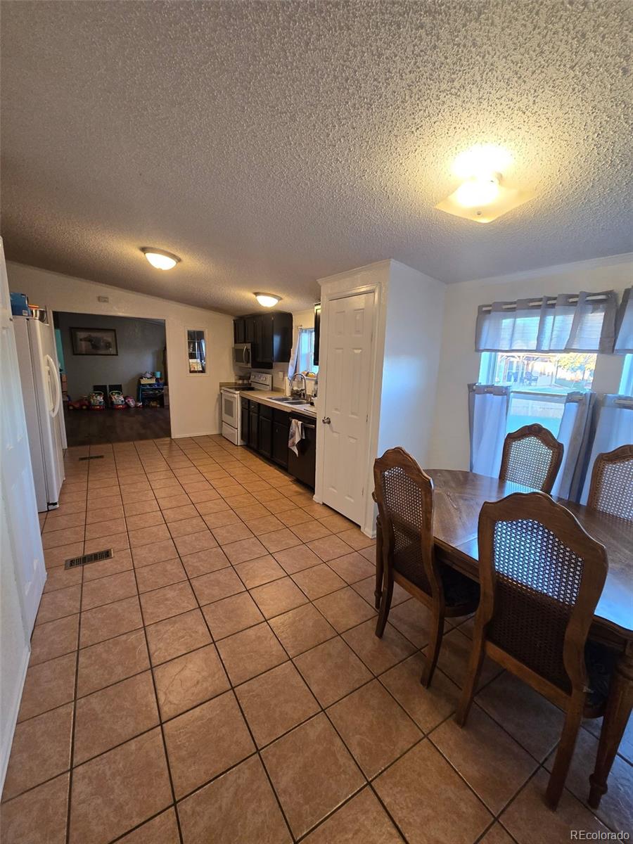 3439 West 3rd Street Road Greeley, CO 80631 - Photo 21 of 31 a kitchen with granite countertop a stove a sink a dining table and chairs