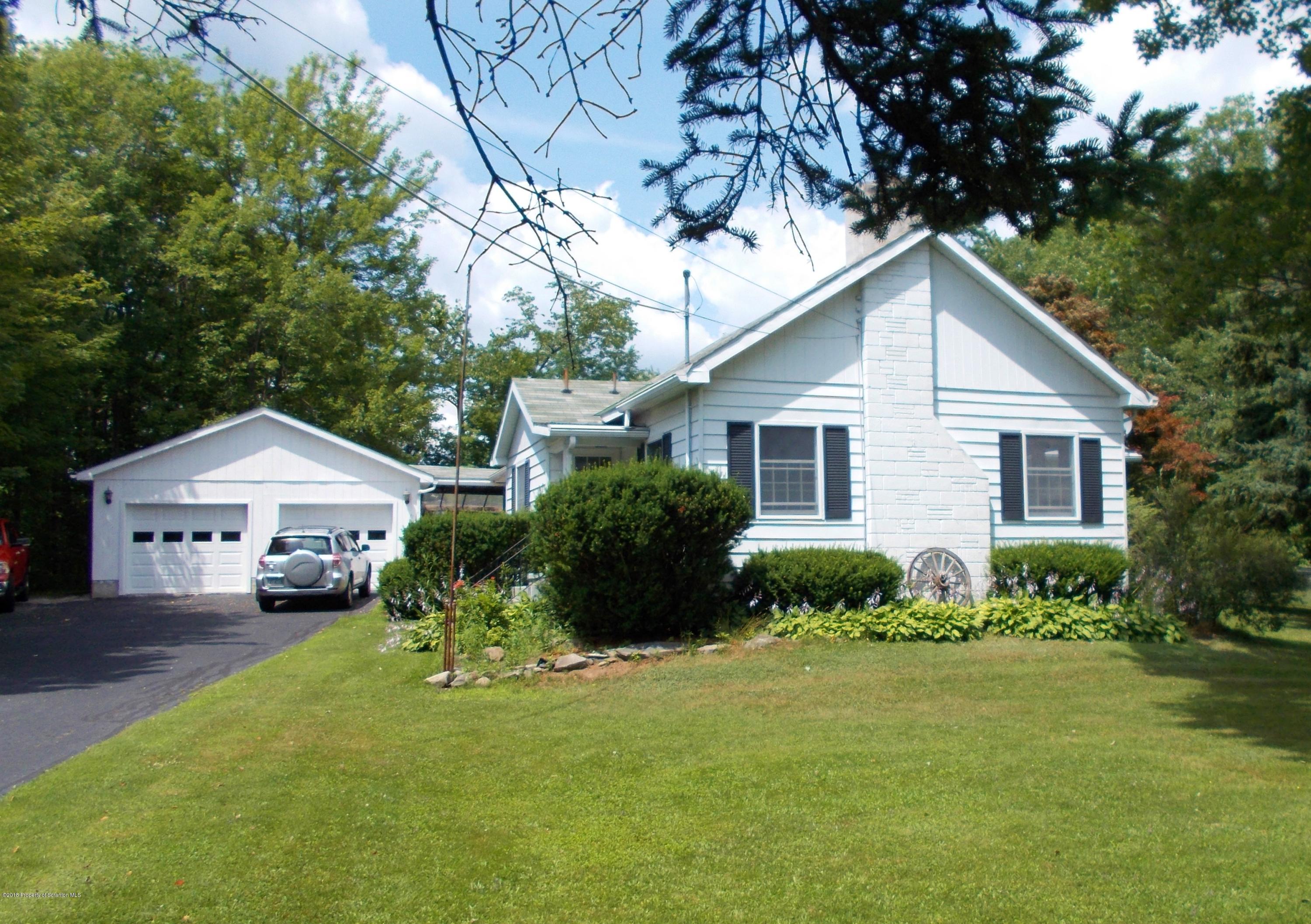577 Pa-rt690 Road Moscow, PA 18444 - Photo 1 of 16 a front view of a house with a garden and trees