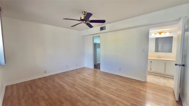 a view of empty room with wooden floor and ceiling fan