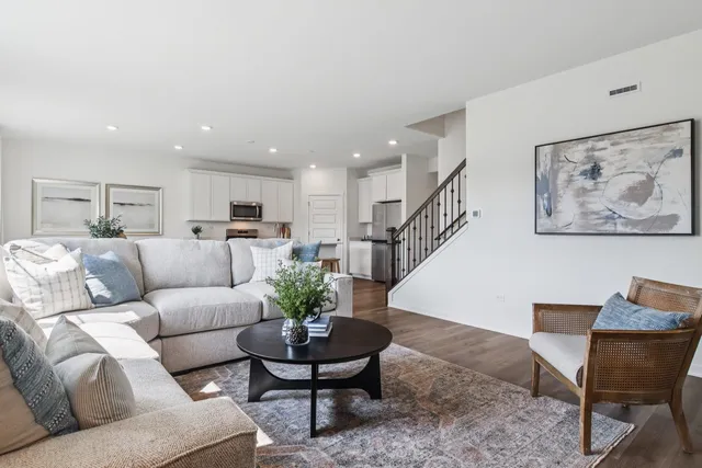 a living room with furniture potted plant and kitchen view