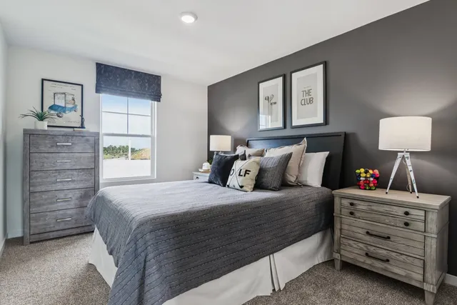 a bedroom with a bed a lamp on dresser and a window