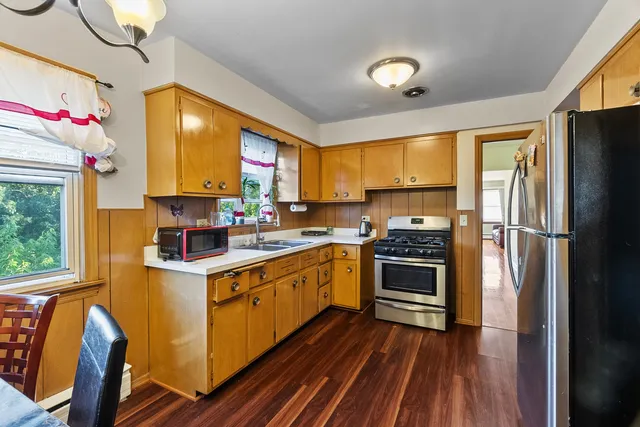 a kitchen with stainless steel appliances granite countertop a refrigerator a sink dishwasher a stove and white countertops with wooden floor