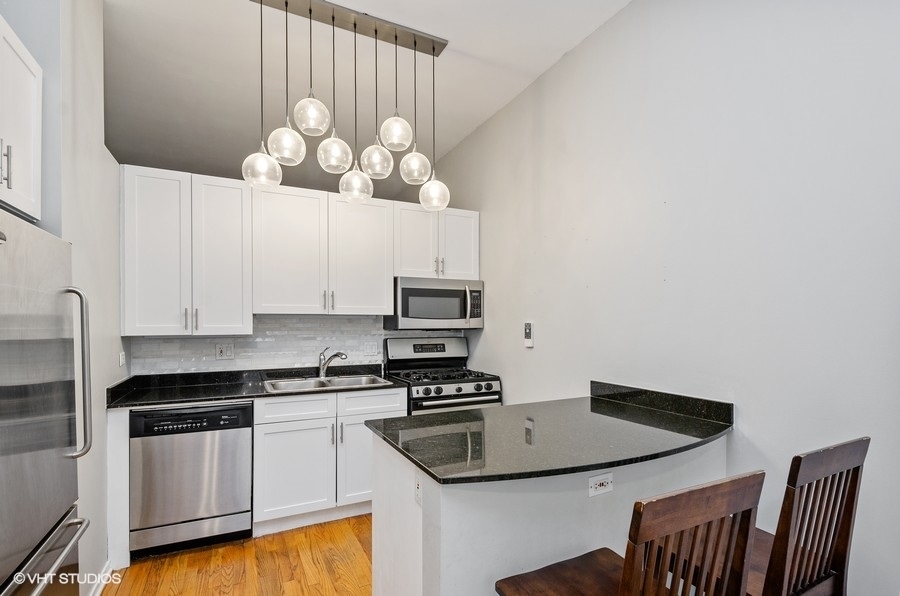 1201 West Adams Street, Unit 609 Chicago, IL 60607 - Photo 5 of 13 a kitchen with stainless steel appliances granite countertop a sink and a stove