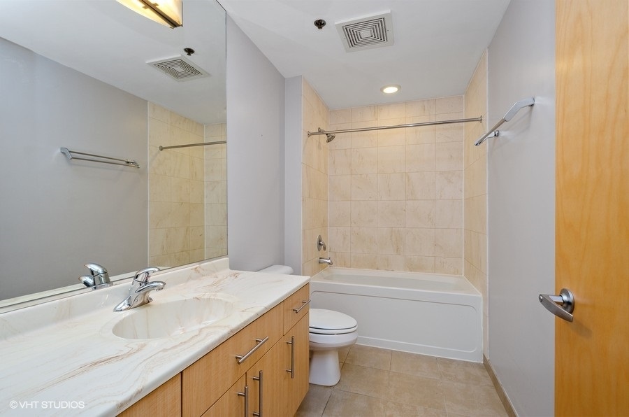 1201 West Adams Street, Unit 609 Chicago, IL 60607 - Photo 10 of 13 a bathroom with a double vanity sink toilet mirror and shower