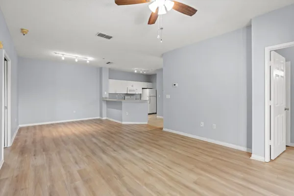 a view of empty room with wooden floor and ceiling fan