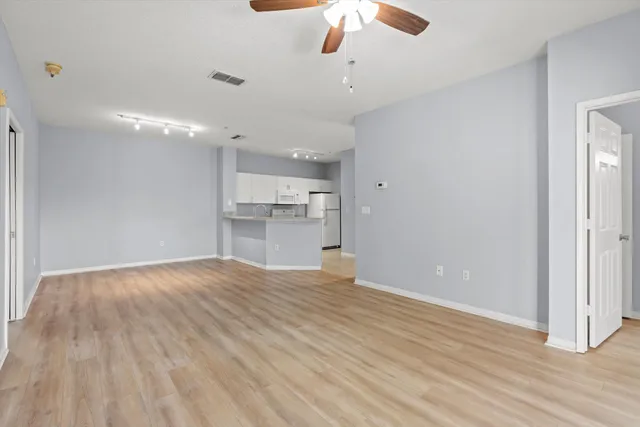 a view of empty room with wooden floor and ceiling fan